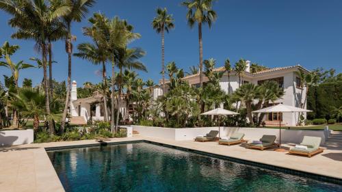 una piscina frente a una casa con palmeras en LVone, Villa in Los Verdiales, Golden Mile, en Marbella