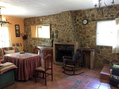 een woonkamer met een stenen open haard en een tafel bij Casa Rosalejo by CasaTuristica in Ronda