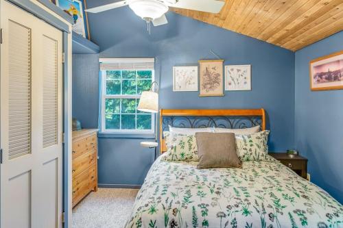 Dormitorio azul con cama y ventana en Tri-Mountain: Home base for exploring the mountains., en Packwood