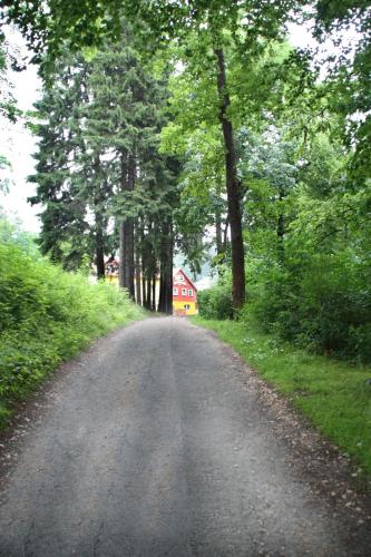 a dirt road with trees and a red house in the distance at Harmont Montis- dawna Zającówka- IDEALNA lokalizacja - leśna enklawa w centrum miasta! Sauna, masaże, zabiegi spa! in Szklarska Poręba