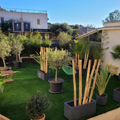 un jardin avec des plantes en pot et des arbres sur l'herbe dans l'établissement LE MAZET, à Saint-Raphaël