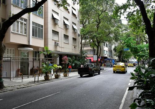um carro amarelo dirigindo por uma rua da cidade com edifícios em Studio Miguel Lemos no Rio de Janeiro
