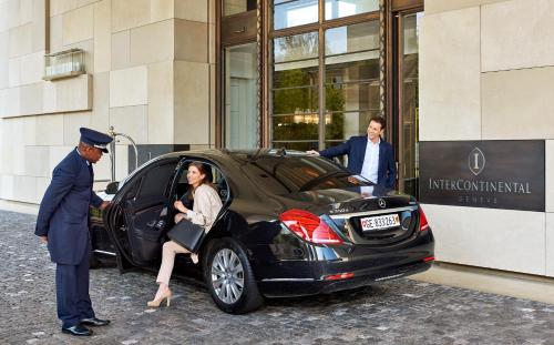 Een man en een vrouw stappen in een auto buiten een gebouw bij InterContinental Genève, an IHG Hotel in Genève