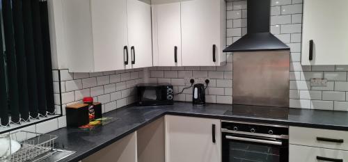 cocina con armarios blancos y fogones en 3 Bedroom Home - Nerby City Centre, en Nottingham
