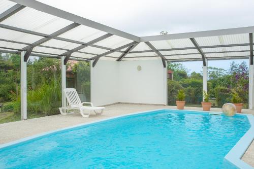 einen Pool mit einer Pergola neben einem Pool in der Unterkunft Hôtel & Restaurant La Ferme Du Pommeau in La Plaine des Palmistes