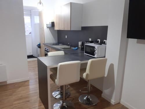 a kitchen with a counter with chairs and a microwave at Lens Louvre 2 in Lens