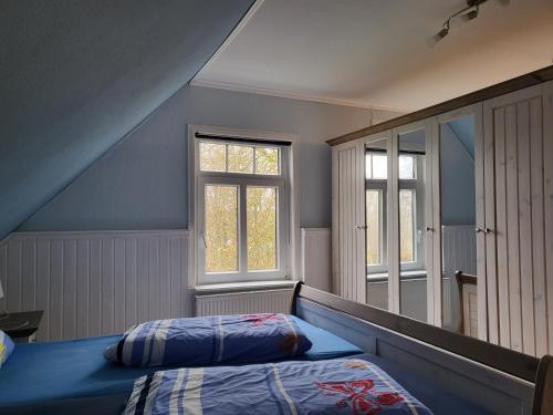 a bedroom with a bed and two windows at Urlaub im blauen Haus in Sehestedt