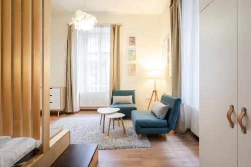 a living room with two blue chairs and a table at GoldenFeet Studio in Budapest