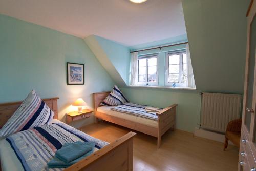 a small bedroom with two beds and a window at Oome Tilles Hüs in Norddorf