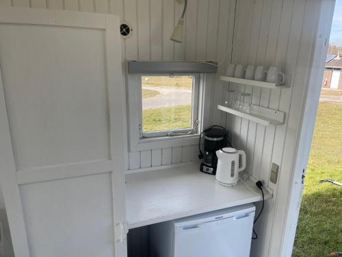 a small kitchen in a tiny house with a window at Tisvildeleje Camping Hytter in Vejby