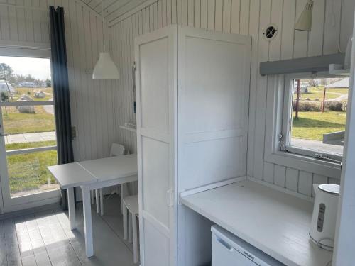 a kitchen with a white cabinet and a table at Tisvildeleje Camping Hytter in Vejby