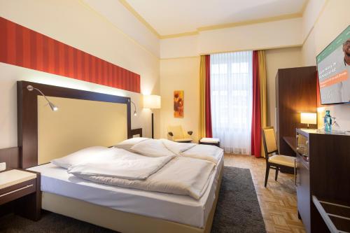 a hotel room with a bed and a desk at ACHAT Sternhotel Bonn in Bonn