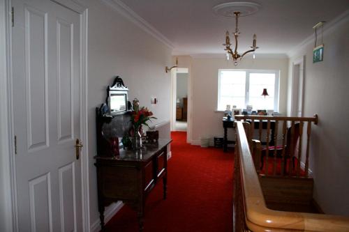 un pasillo con alfombra roja y una habitación con reloj en Ballyharvey B&B en Antrim