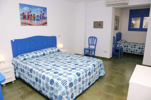 1 dormitorio con 1 cama azul y 2 sillas azules en Pensió Solivent, en L'Escala