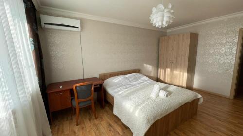 a bedroom with a bed and a desk and a chair at На Тархана in Astana