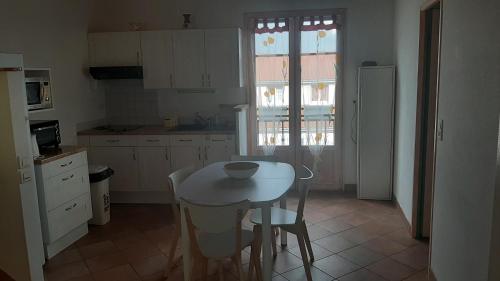 una cocina con una pequeña mesa blanca y sillas en Charmant Logement T2 campagne 