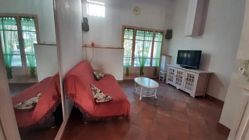 a living room with a red couch and a tv at Charmant Logement T2 campagne 