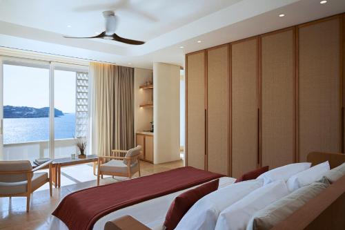 a bedroom with a bed and a desk and a window at Bill & Coo Suites and Lounge -The Leading Hotels of the World in Mikonos