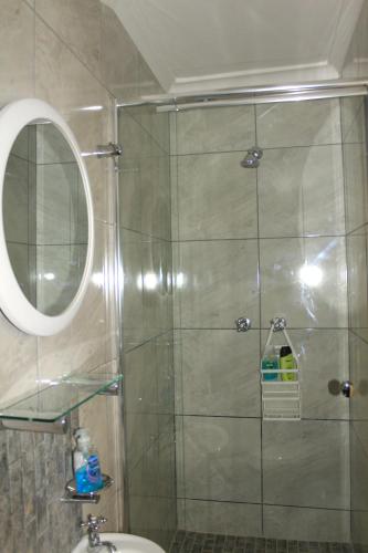 a bathroom with a shower with a mirror and a sink at South Peninsula Beach Apartment in Cape Town