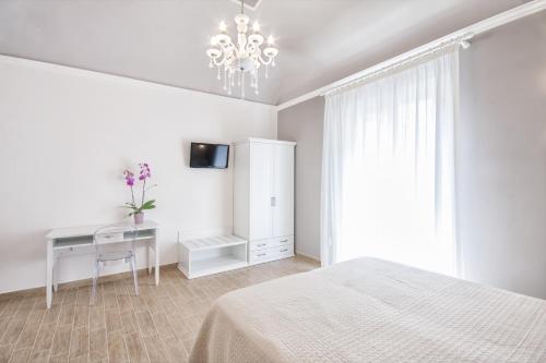 a white bedroom with a bed and a desk at Residenza Le Zagare in Castellammare del Golfo