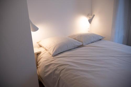 1 cama blanca con 2 almohadas y una mesita de noche en au42dotBzh, en Saint-Brieuc