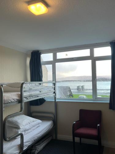 a room with bunk beds and a window and a chair at Saucy Mary's Hostel in Kyleakin