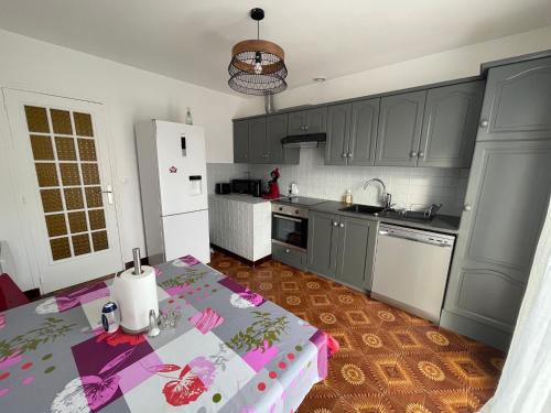 uma cozinha com armários cinzentos e uma mesa com uma toalha de mesa em Super maison entre paris et Disney em Chelles