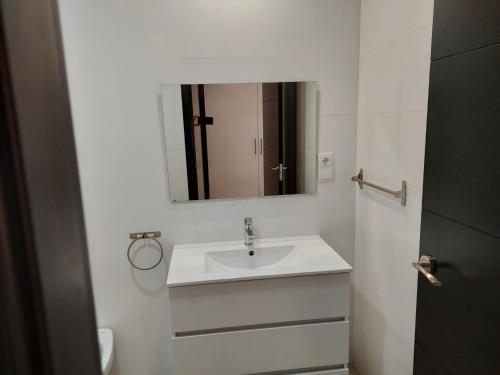 a white bathroom with a sink and a mirror at Hostal GARDEN ROUS in Paiporta
