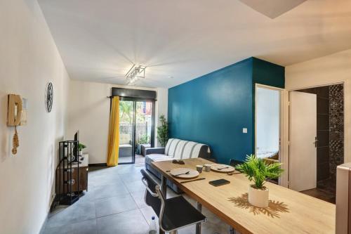 ein Esszimmer mit einem Tisch und einer blauen Wand in der Unterkunft Le Zévi - appt T2 Saint Denis in Saint-Denis