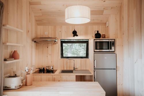 a kitchen with wooden walls and a refrigerator and a window at Domaine St-Amand in Saint-Amand-de-Coly