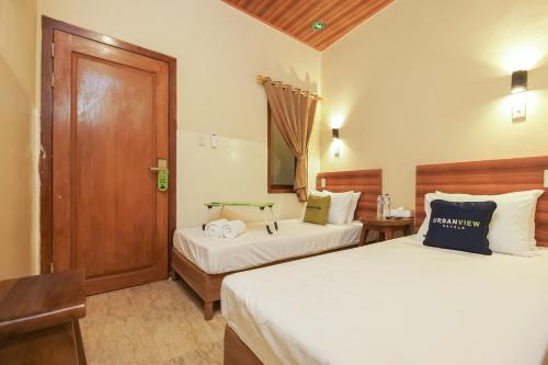 a bedroom with two beds and a wooden door at Urbanview Hotel Cantee Halim Perdanakusuma by RedDoorz in Jakarta
