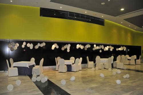a room with white chairs and tables and a yellow wall at Hotel Salobreña Suites in Salobreña