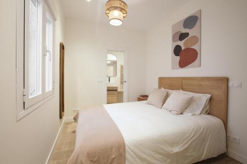 a white bedroom with a large bed with white sheets at Luxury flat next to Gran Via Madrid in Madrid