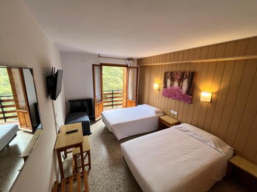 um quarto de hotel com duas camas e um sofá em Meson de Castiello em Castiello de Jaca