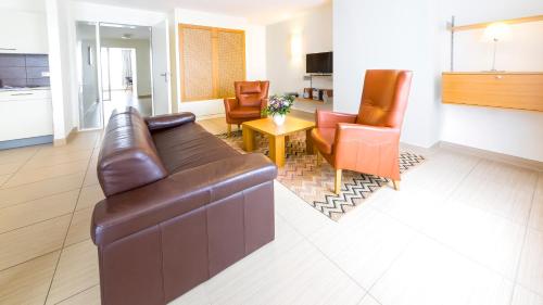 ein Wohnzimmer mit einem braunen Ledersofa und Stühlen in der Unterkunft Michels Villa Nordsee in Norderney