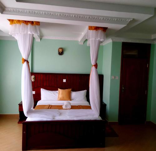 a bedroom with a canopy bed with white curtains at Monrovia Guest House in Nakuru