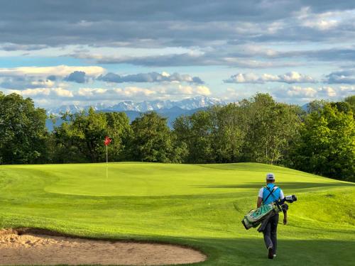 Un homme se promène sur un parcours de golf vert dans l'établissement Seenswert - Vegane Pension und Ferienwohnungen am Ammersee, à Pähl