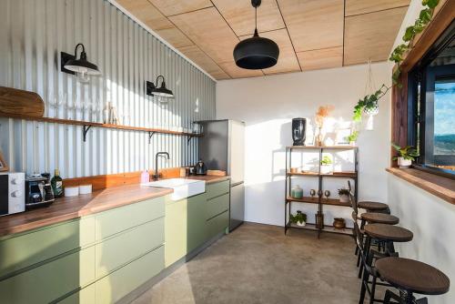 a kitchen with green cabinets and a sink and stools at Cicada Luxury Camping in Kiama