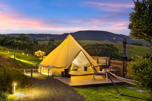 Tenda con tavolo e sedia su una terrazza in legno di Cicada Luxury Camping a Kiama