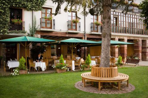 a patio with a tree and a table and umbrella at Hotel Echaurren Relais & Châteaux in Ezcaray