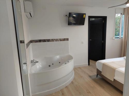 a bathroom with a tub and a bed and a television at Hostal GARDEN ROUS in Paiporta