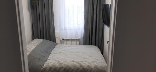 a small bedroom with a bed in front of a window at APARTAMENT Klasztorna Centrum Nowy Sącz in Nowy Sącz