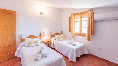 Almáchar的住宿－Casa Caribe Almáchar by Ruralidays，一间卧室设有两张床和窗户。