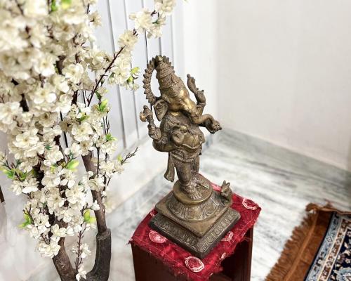 a statue sitting on a red table next to flowers at Radha Krishna Bhawan, Homestay in Vrindāvan