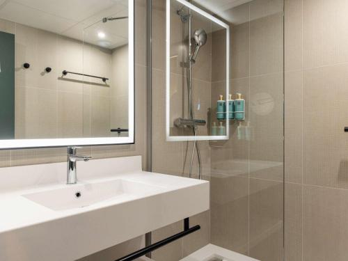 ein Bad mit einem Waschbecken und einer Dusche in der Unterkunft Novotel Paris Suresnes Longchamp in Suresnes