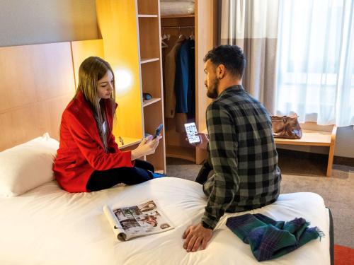 a man and a woman sitting on a bed at ibis Hotel Brussels Centre Gare du Midi in Brussels