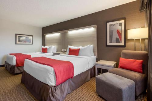 a hotel room with two beds and a chair at Best Western Plus Village Park Inn in Calgary