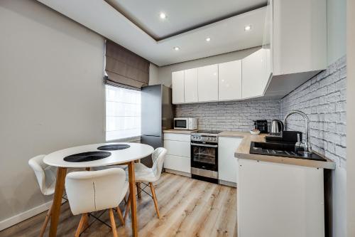 Una cocina con gabinetes blancos y una mesa y sillas. en Central Platinum Apartments 31, en Rybnik