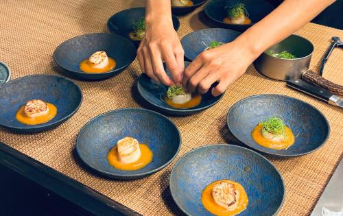 a person is making food in blue plates on a table at Zephyr Homestay in Yanliau
