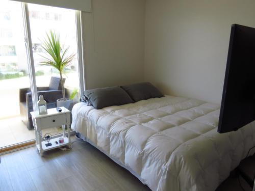 a large bed in a room with a large window at Departamento AltoMar El Tabo Isla Negra in El Tabo